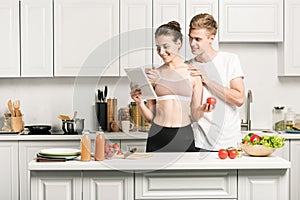 young couple reading recipe for healthy food on tablet