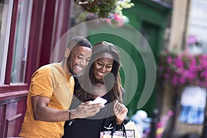 A young couple reading a text message together oin the street