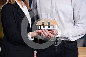 Young couple, realtor holding 3d model of house.