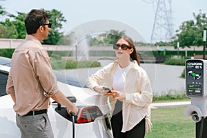 Young couple recharge electric car& x27;s battery from charging station. Expedient