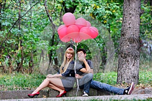 Young couple with red balloons on nature