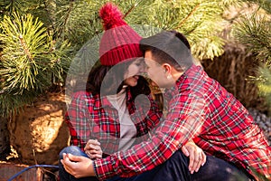 Young couple in red checkered shirts kissing, holding festive sparklers. Christmas tree market