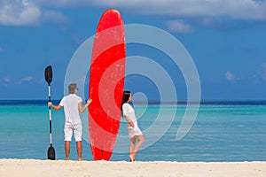 Young couple with red surfboard during tropical