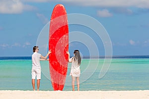 Young couple with red surfboard during tropical vacation