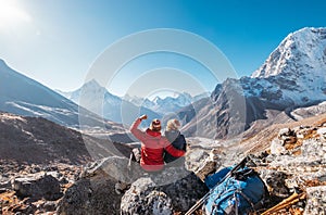 Young couple rejoicing on Everest Base Camp trekking route near Dughla 4620m. Backpackers left Backpacks and trekking poles and