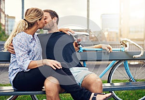 Young couple relaxing on a bench enjoying a kiss