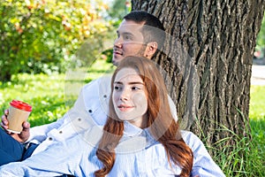 Young couple relaxing with coffee under tree