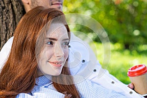 Young couple relaxing with coffee under tree