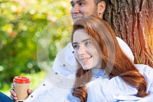 Young couple relaxing with coffee under tree