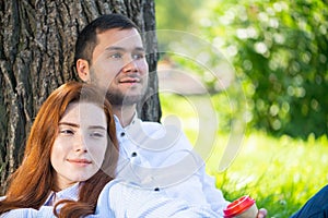 Young couple relaxing with coffee under tree