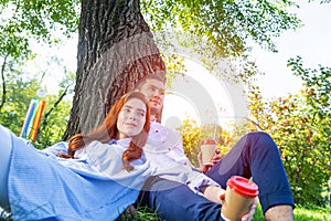 Young couple relaxing with coffee under tree