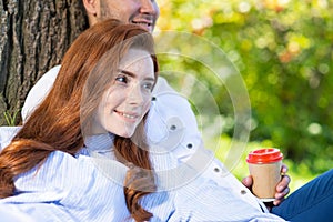 Young couple relaxing with coffee under tree