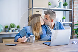 Young couple relaxing drinking a coffee and using the computer laptop around cardboard boxes, very happy moving to a new house