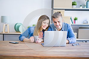 Young couple relaxing drinking a coffee and using the computer laptop around cardboard boxes, very happy moving to a new house