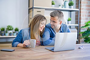 Young couple relaxing drinking a coffee and using the computer laptop around cardboard boxes, very happy moving to a new house