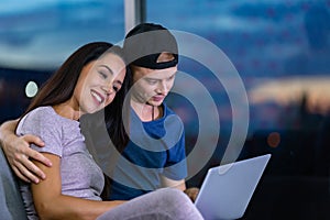 Young couple relaxing and enjoying at home on sofa with laptop