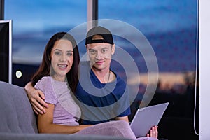 Young couple relaxing and enjoying at home on sofa with laptop