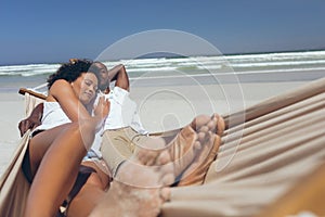 Young couple relaxing on hammock at beach on sunny day
