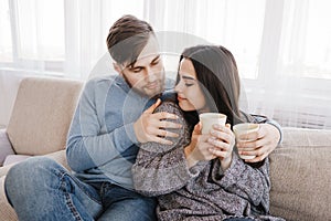 Young couple relaxing at home with hot drinks