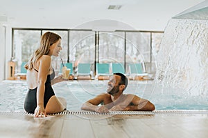 Young couple relaxing by the indoor swimming pool