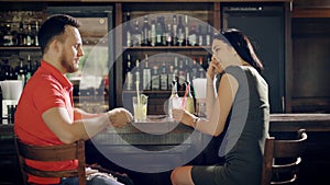 Young couple relaxing in a pub sitting at bar counter and drinking beverageMen and women dressed in casual clothes are