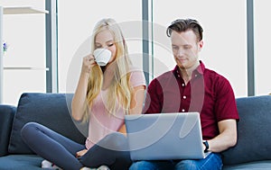 Young couple relaxing on sofa with laptop