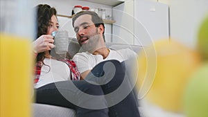 Young couple relaxing in their apartment, lying on the couch and watching the movie.