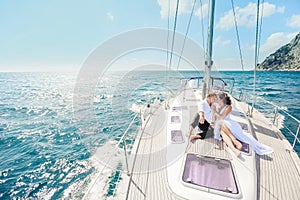 Young Couple Relaxing on a Yacht. Happy wealthy man and a woman by private boat have sea trip. photo