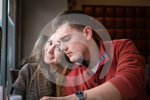 Young couple in a restaurant sitting at a table by the window and make an order. Two persons