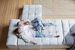 Young couple resting at home on couch, top view, copy space. Domestic life