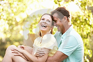 Young Couple Resting On Tree In Park