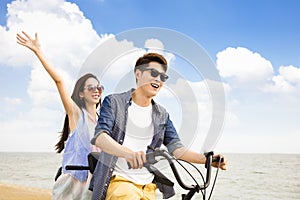 Young couple riding bicycle on the beach