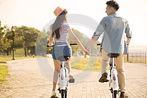 Young couple riding on bicycle in city park