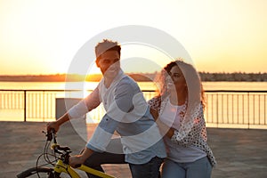 Young couple riding bicycle on city waterfront