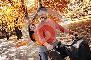 Young couple riding a bicycle on a sunny autumn day. The park is colorful