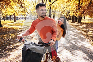 Young couple riding a bicycle on a sunny autumn day. The park is colorful