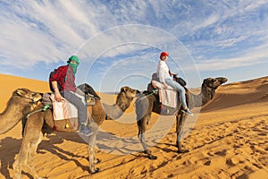Young couple riding a camel in the middle of a desert in marocco