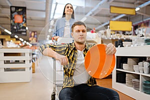 Young couple riding on cart in houseware store