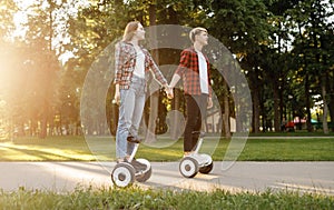 Young couple riding on gyroboard in park at sunset