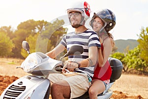 Young Couple Riding Motor Scooter Along Country Road