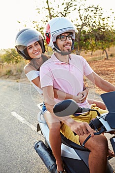 Young Couple Riding Motor Scooter Along Country Road