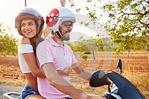 Young Couple Riding Motor Scooter Along Country Road