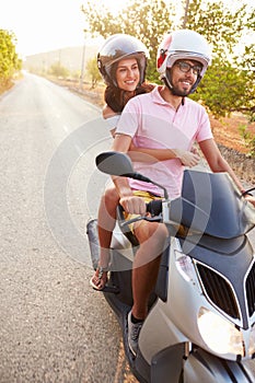 Young Couple Riding Motor Scooter Along Country Road