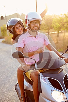 Young Couple Riding Motor Scooter Along Country Road