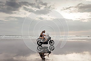 Young couple riding motorcycle on the beach