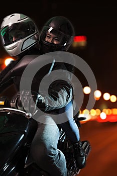 Joven sobre el caballo motocicleta través de la ciudad calles por la noche en 