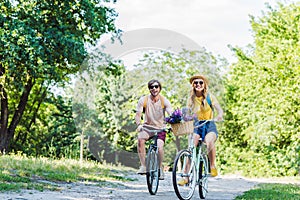 young couple riding retro bicycles in park