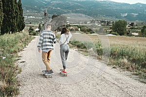 Young couple riding a skateboard on a road. Concept of millenials Skateboarders photo