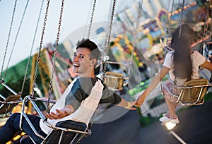 Young couple riding the swings at an amusement park