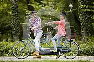 Young couple riding on the tandem bicycle